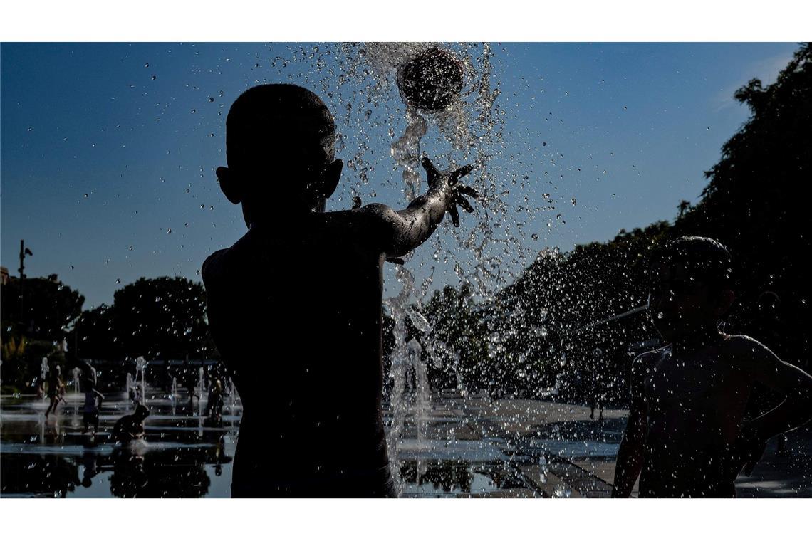 Kinder spielen mit einem Ball in einem Springbrunnen in Nizza.