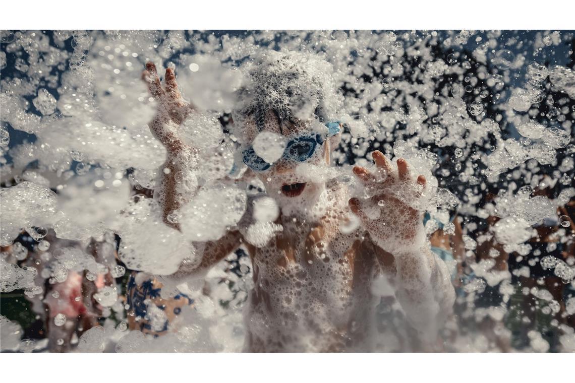 Kinder werden mit Schaum bedeckt, als sie während des traditionellen Sant Marti Festivals in Es Mercadal an einer Schaumparty teilnehmen.