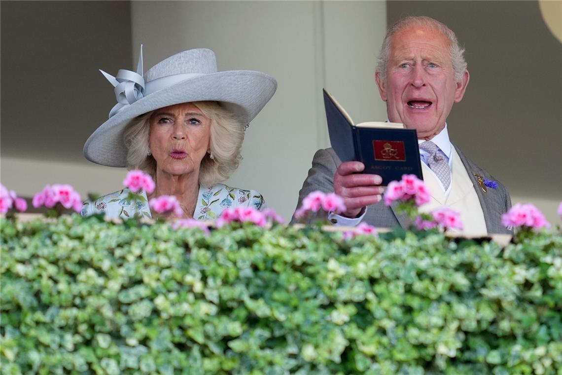 Königin Camilla setzt am ersten Tag von Royal Ascot auf einen klassisch-eleganten Look: einen breitkrempigen hellgrauen Hut mit skulpturaler Schleifendekoration, kombiniert mit einem hellen, floral bestickten Outfit.