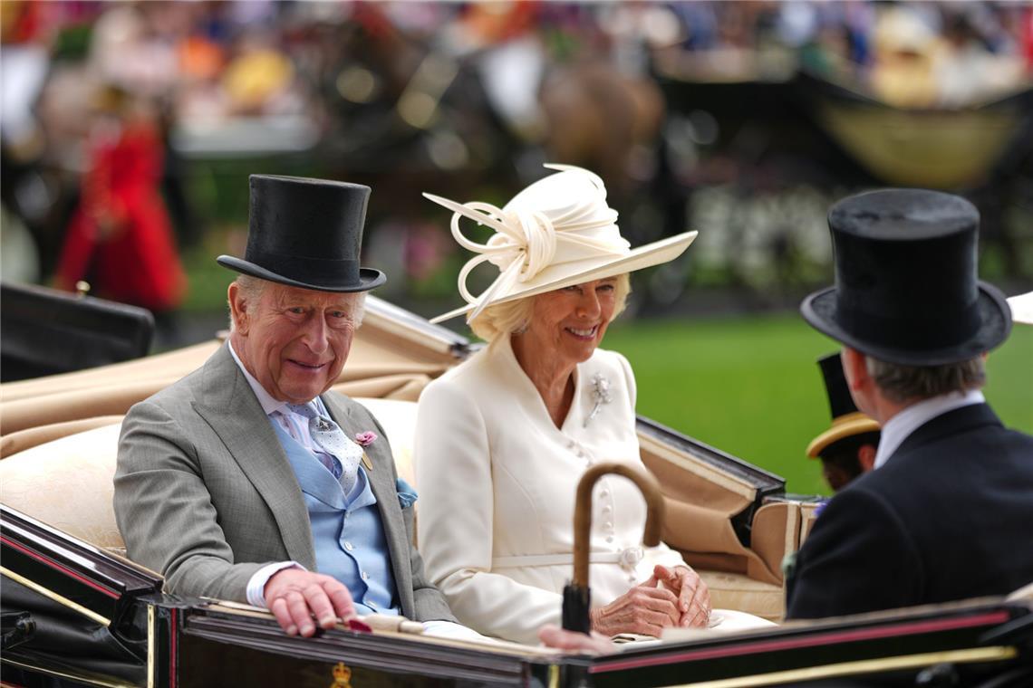 Königin Camilla zeigt am zweiten Tag von Royal Ascot einen cremeweißen Look mit passendem Hut: Der schräg sitzende Kopfschmuck ist mit skulpturalen Schleifen und feinen Stäben verziert, dazu trägt sie ein helles Mantelkleid mit Brosche.
