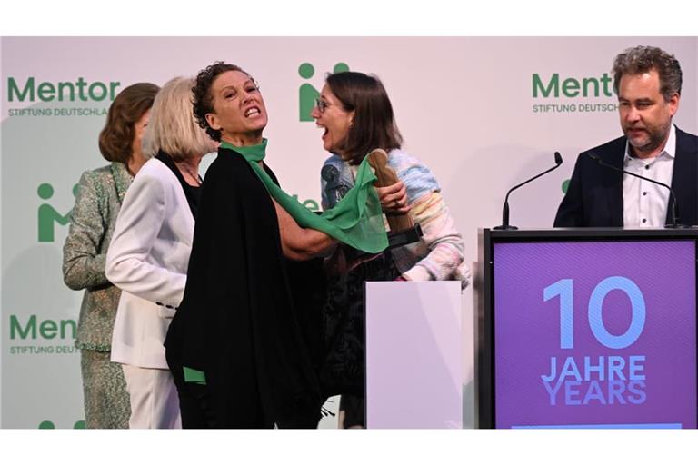 Königin Silvia von Schweden (l) und Bettina Gräfin Bernadotte (r) schauen zu, wie Sybille Perez (3.v.l), Leitung Mentor-Akademie, den Preis wieder aufhebt, der auf den Boden gefallen ist.
