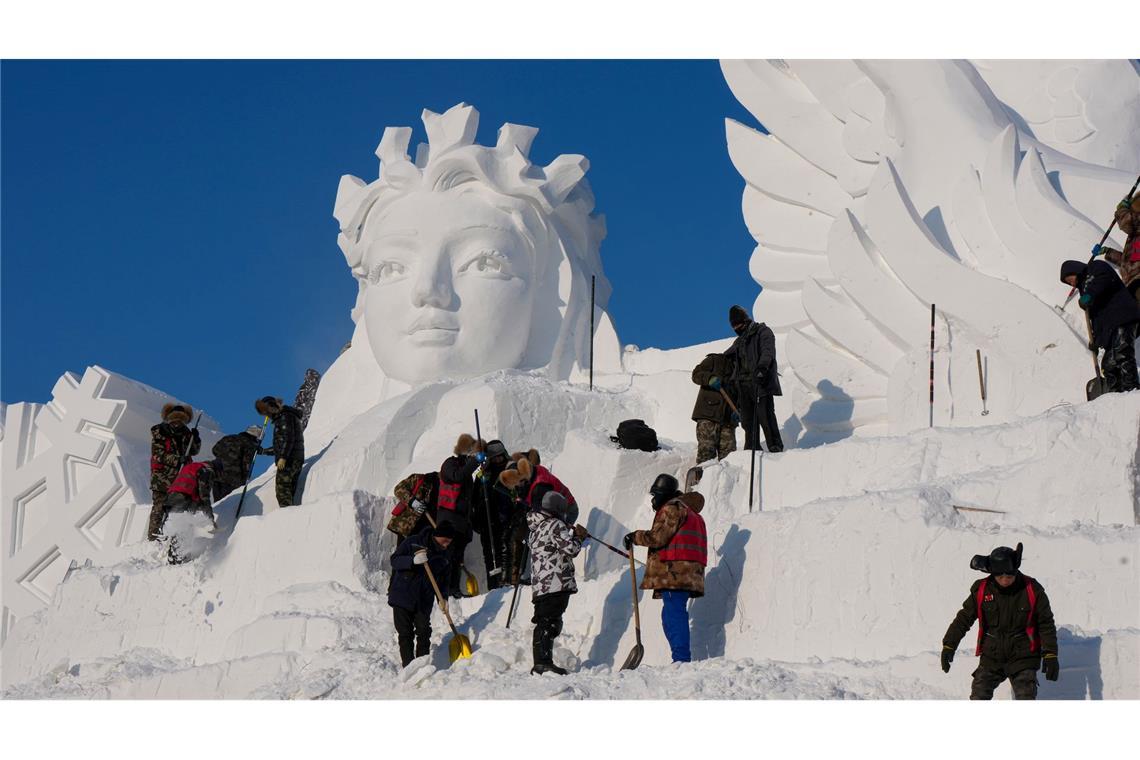 Künstler arbeiten an einer Schneeskulptur.