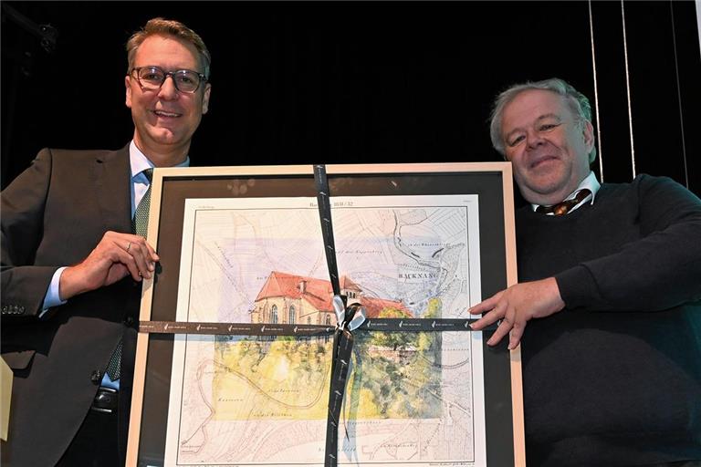 Landrat Richard Sigel (links) hat zum Jubiläum des Museums ein besonderes Geschenk mitgebracht – ein Aquarell der Backnanger Stiftskirche von Werner Drauz. Christian Schweizer nimmt es entgegen. Foto: Elisabeth Klaper