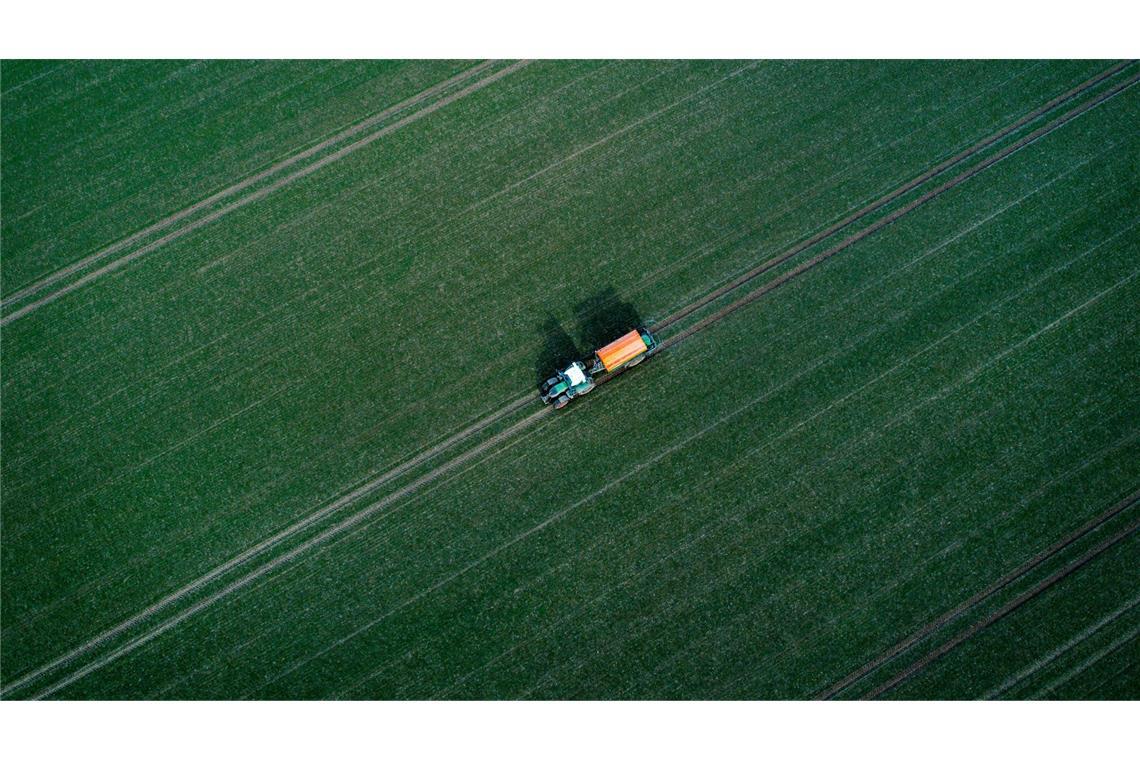 Bilder des Tages Landwirtschaftstag in Mecklenburg-Vorpommern - Mit einem Traktor zieht ein Landwirt einen Düngerstreuer zum Beginn der Agrarsaison über einen Acker.