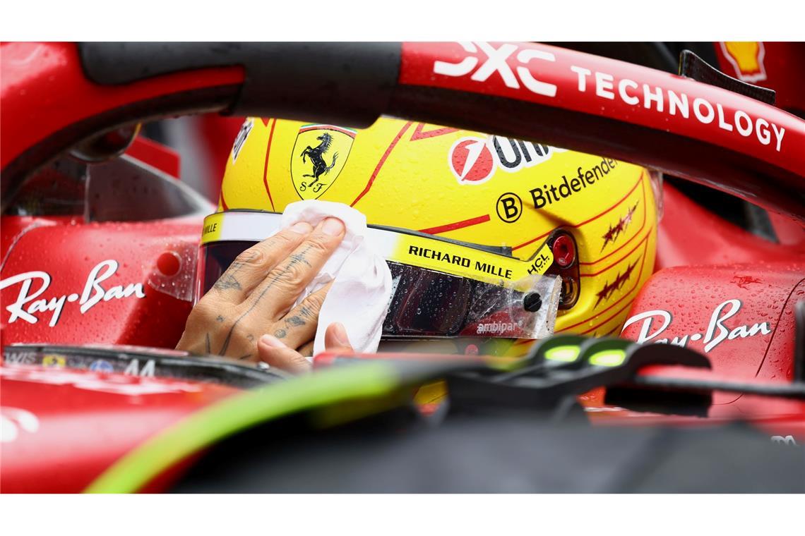 Lewis Hamilton wischt sich den Regen vom Visier.