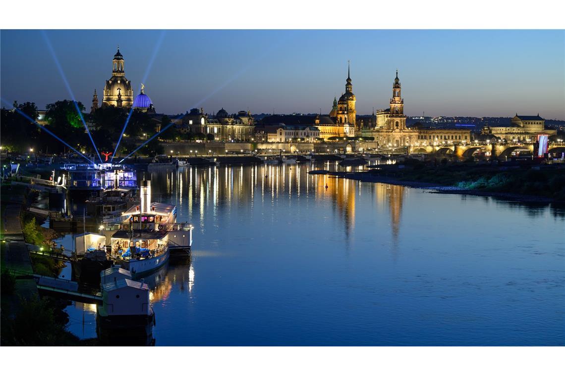 Lichter einer Party auf einem Schiff der Sächsischen Dampfschifffahrt Weiße Flotte sind am Abend vor der historischen Altstadtkulisse in Dresden an der Elbe mit der Frauenkirche (l-r), der Kuppel der Kunstakademie mit dem Engel „Fama“, dem Terrassenufer, dem Ständehaus, dem Hausmannsturm, der Hofkirche und der Semperoper zu sehen.
