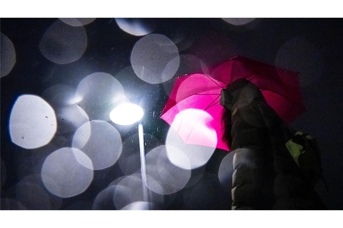 Bilder des Tages Lichtspiel in der Dunkelheit: Eine Frau mit Regenschirm geht am frühen Morgen in Bremen über eine Brücke über die Weser.
