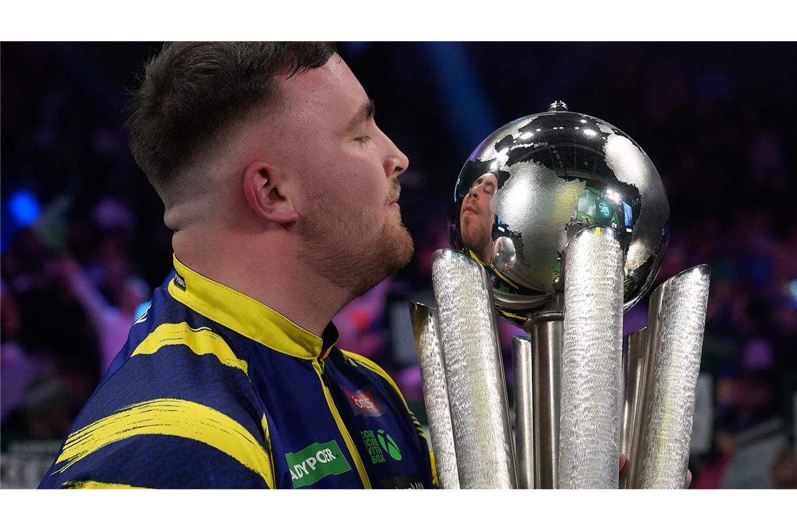 Luke Littler küsst die Trophäe nach seinem Sieg im Endspiel der Darts-WM.