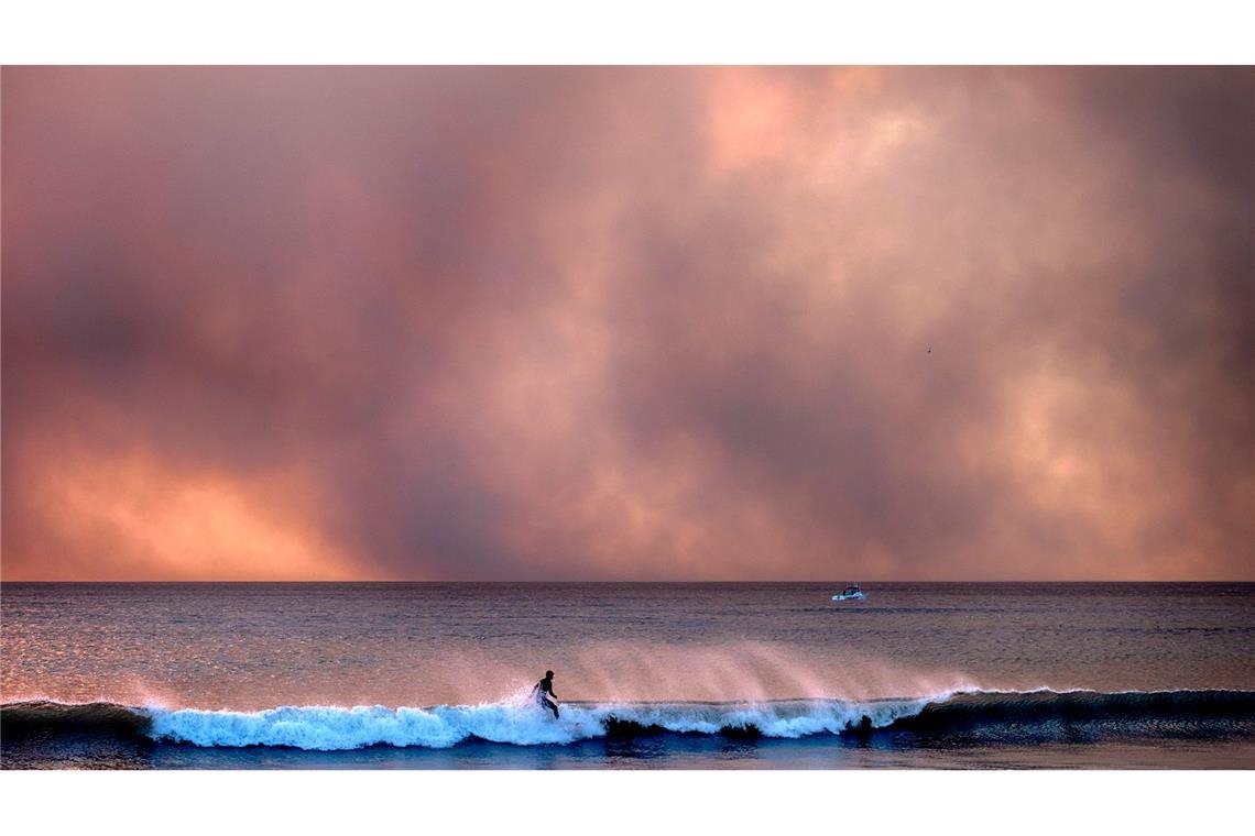 Bilder des Tages Manchen lassen die Waldbrände in auch Kalifornien kalt: Dieser Surfer reitet auf einer Welle, während Rauch den Himmel verdunkelt.