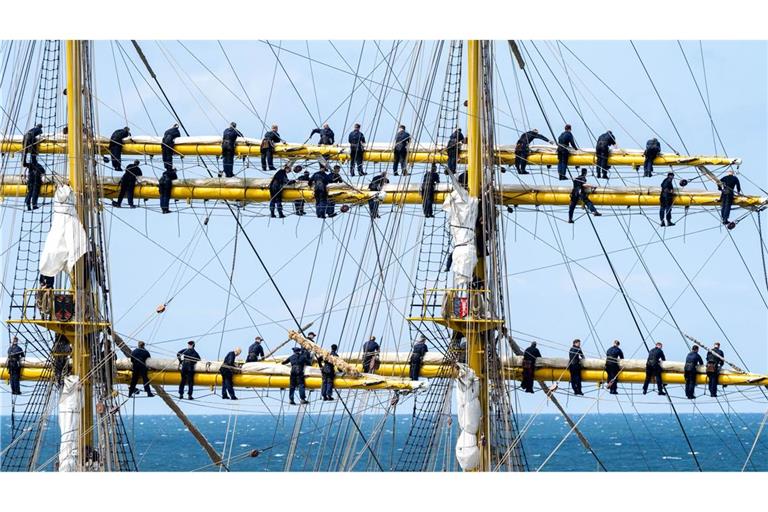 Marinesoldaten stehen bei der Ausfahrt aus dem Hafen Warnemünde an den Rahen auf dem Segelschulschiff Gorch Fock.