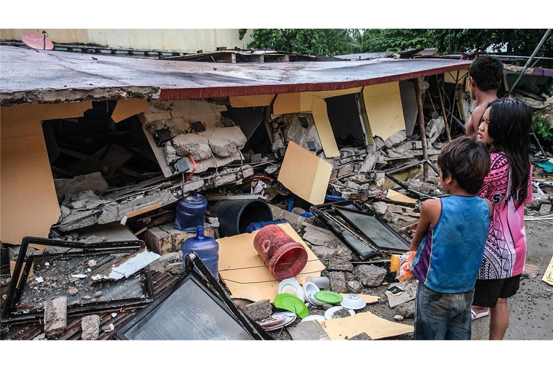 Mindestens 69 Tote nach schwerem Erdbeben auf den Philippinen Menschen betrachten ein eingestürztes Gebäude in Bogo City, Provinz Cebu, nach einem Erdbeben am späten Dienstag.