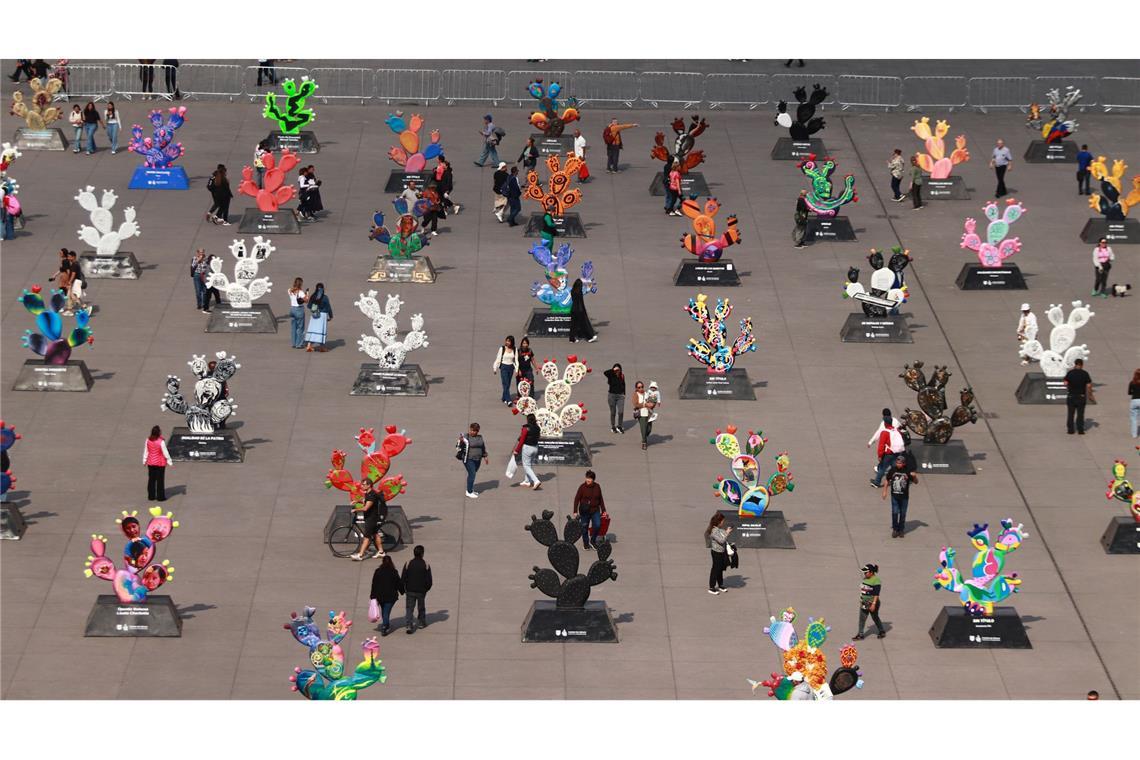 Menschen betrachten monumentalen Skulpturen in Form von Kakteen die von mexikanischen Künstlern gefertigt wurden.