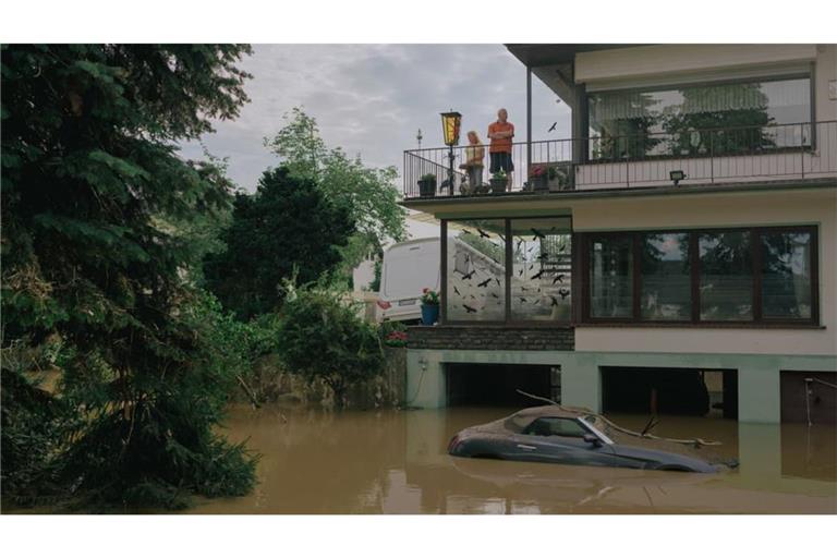Menschen blicken von einem Balkon in Ahrweiler auf die braune Flut: ein Bild des Kollektivs Docks von der Flutkatastrophe 2021. 