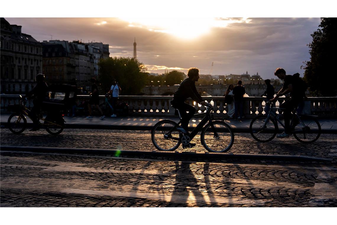 Bilder des Tages Menschen fahren bei Sonnenuntergang mit dem Fahrrad auf einer Brücke über die Seine in Paris.