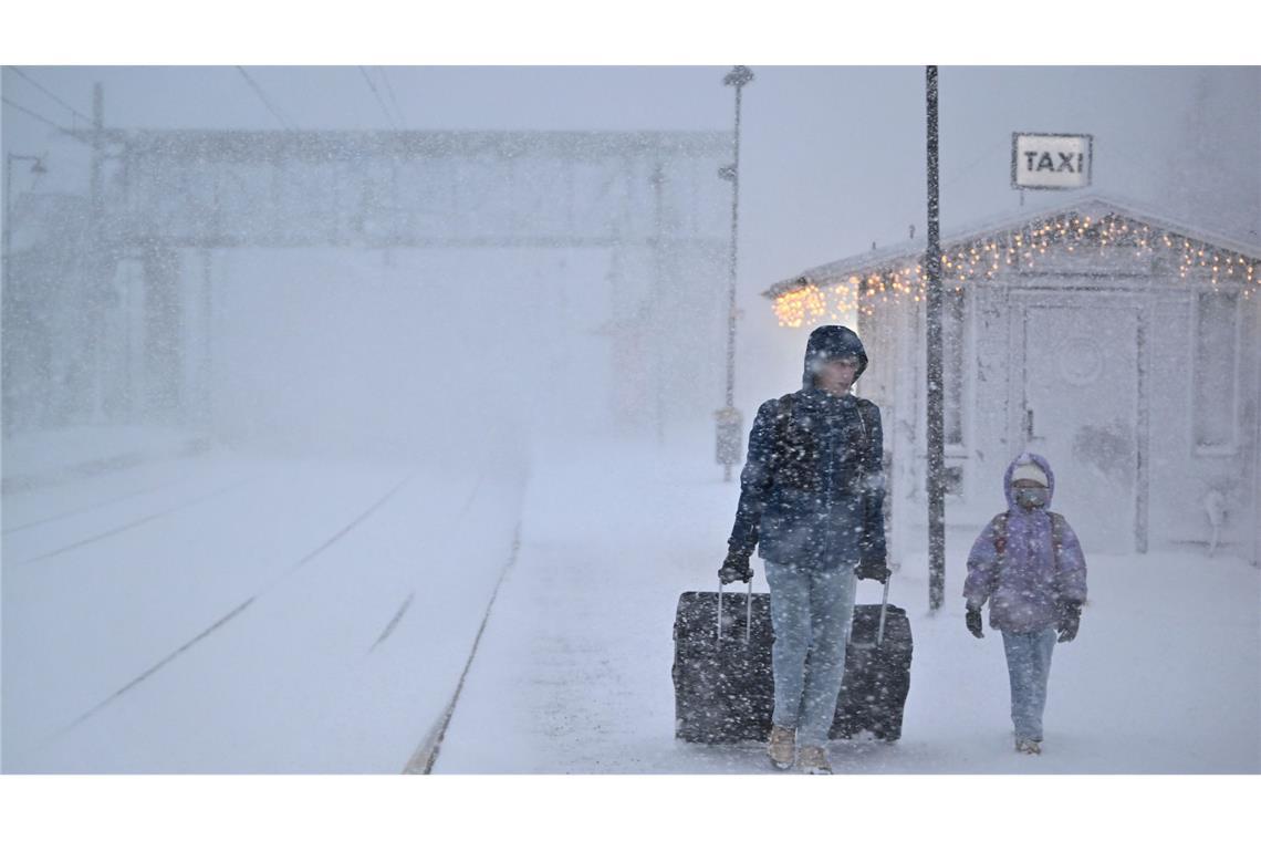 Menschen gehen bei starkem Schneefall am Bahnhof in der Stadt Åre in Schweden, nachdem der Zugverkehr eingestellt wurde.