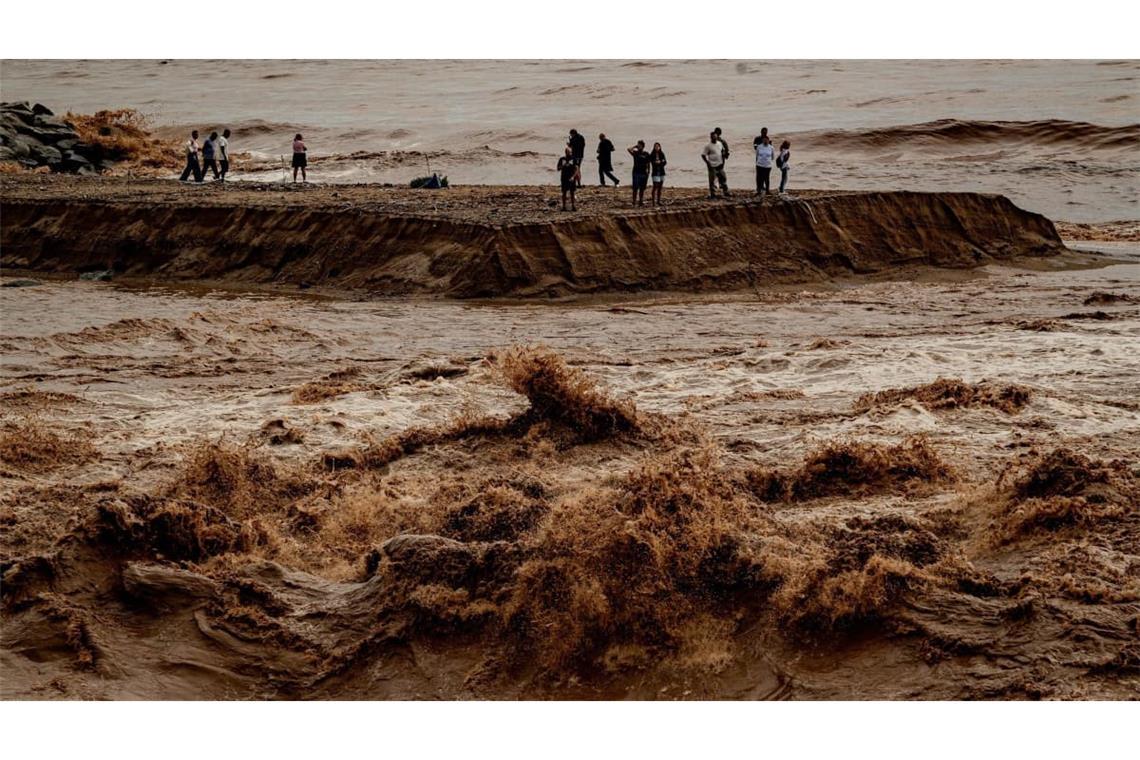 Menschen halten sich an der Mündung des Flusses Besòs nördlich von Barcelona auf, der nach einer Nacht mit sintflutartigen Regenfällen in ganz Katalonien angeschwollen und mit Sedimenten beladen ist.