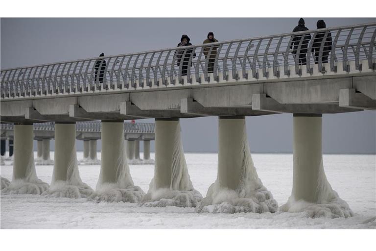 Menschen laufen am 4. Februar auf der eingefrorenen Seebrücke in Prerow. Die längste Seebrücke an der Ostseeküste ist komplett vom Eis umschlossen.