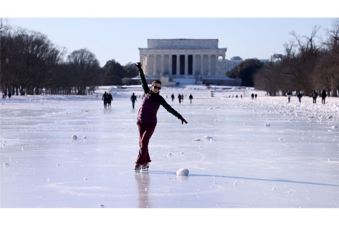 Menschen laufen Schlittschuh auf dem zugefrorenen Wasserbecken vor dem Lincoln Memorial.