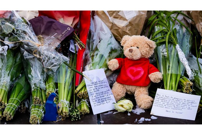 Menschen legen Blumen, Teddys und Botschaften am Brandort ab.