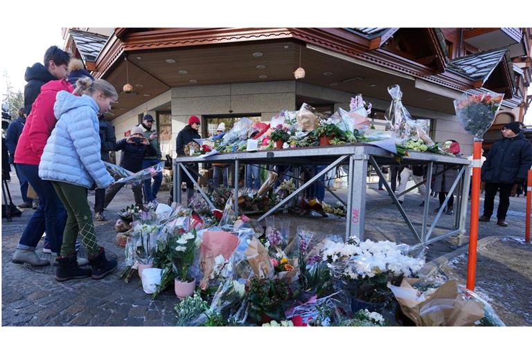 Menschen legen in der Nähe der ausgebrannten Bar Blumen ab.