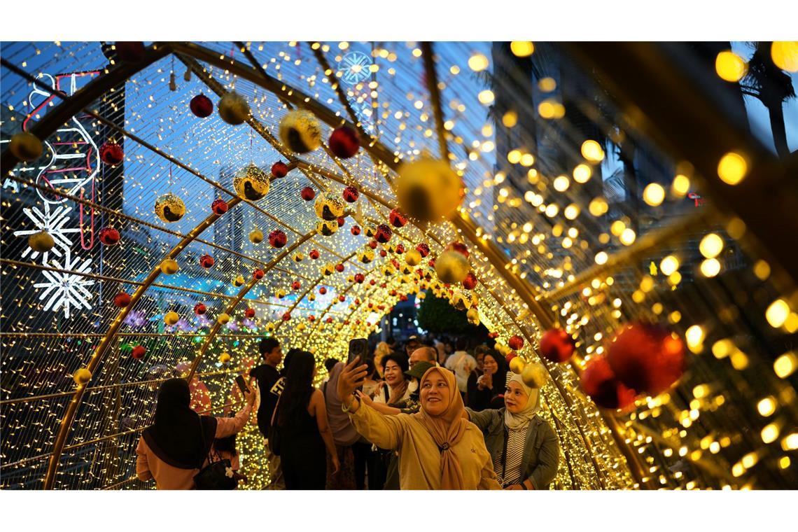 Menschen machen Selfies unter einer Weihnachtsbeleuchtung in Jakarta.