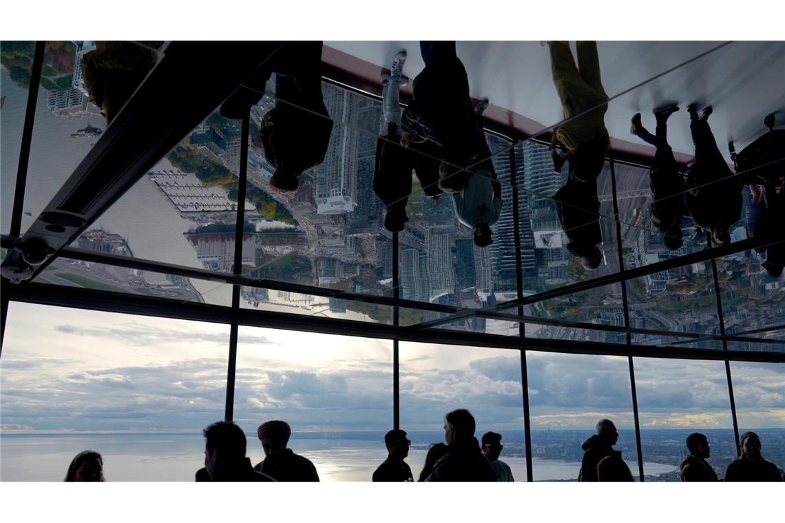 Menschen schauen vom CN Tower in Toronto auf das Rogers Centre und den Ontariosee.