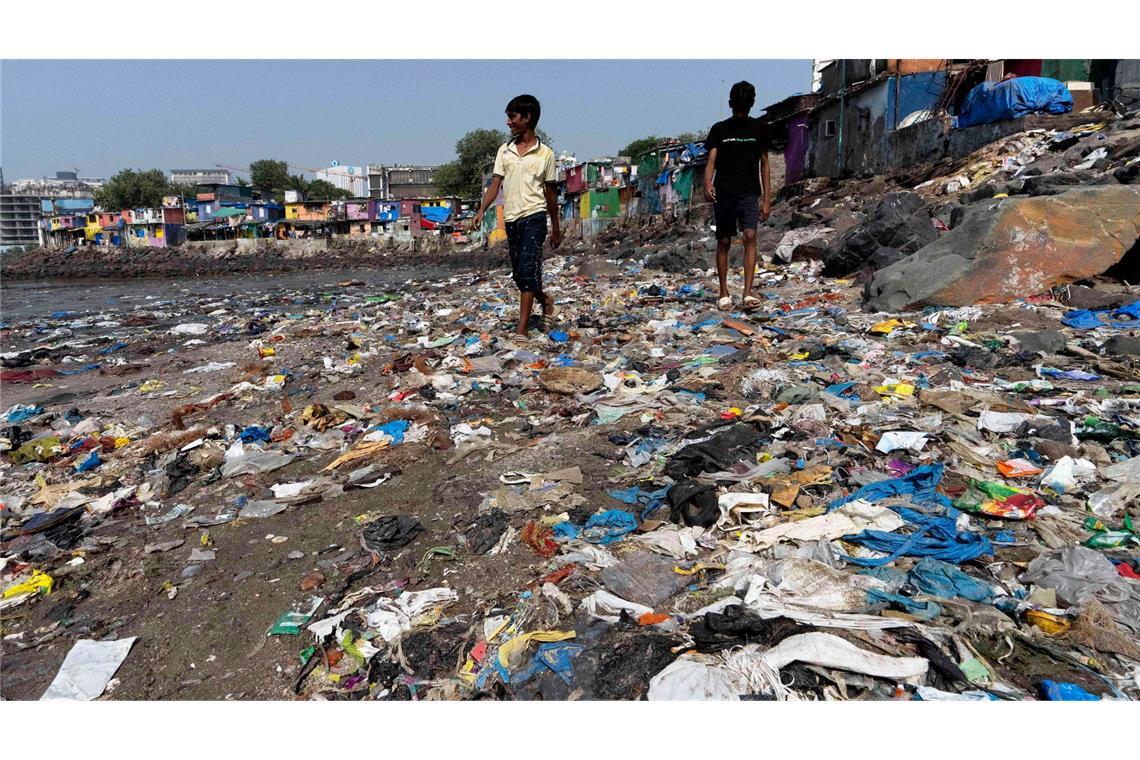 Verhandlungsrunde über UN-Plastikabkommen ohne Einigung Menschen spazieren am Strand des Badhwar Park im indischen Mumbai an Plastikmüll vorbei. (Archivbild)