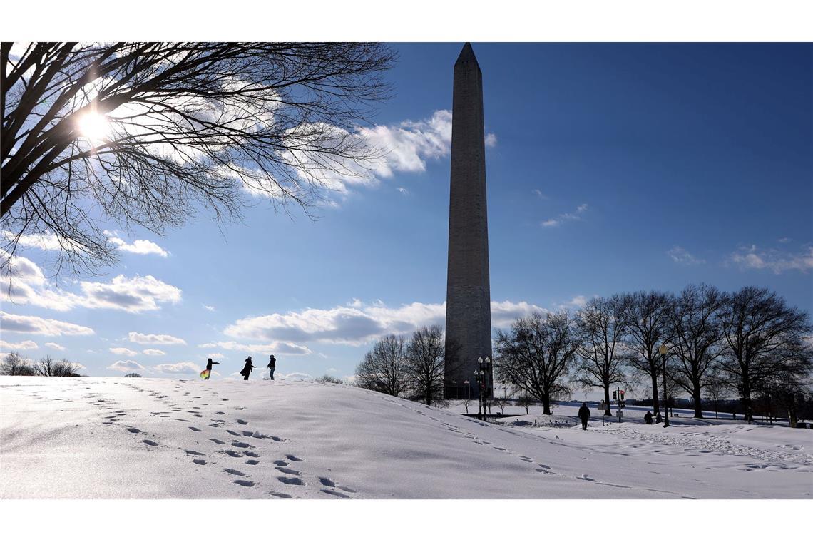 Menschen spazieren im Schnee auf der National Mall.