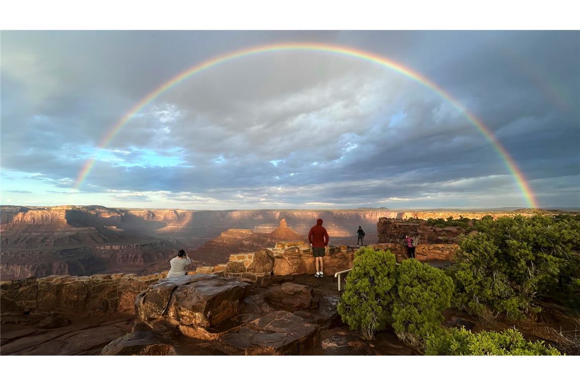 Bilder des Tages Menschen stehen an einem Aussichtspunkt, während ein doppelter Regenbogen am Himmel über dem Dead Horse Point State Park in der Nähe von Moab in den USA leuchtet.