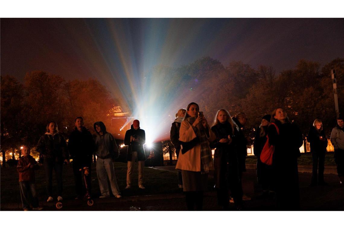 Bilder des Tages Menschen stehen vor einem Beamer, während der Berliner Dom bei der Generalprobe für das 21. Festival of Lights Berlin unter dem Motto „Let’s Shine Together“ angestrahlt wird.