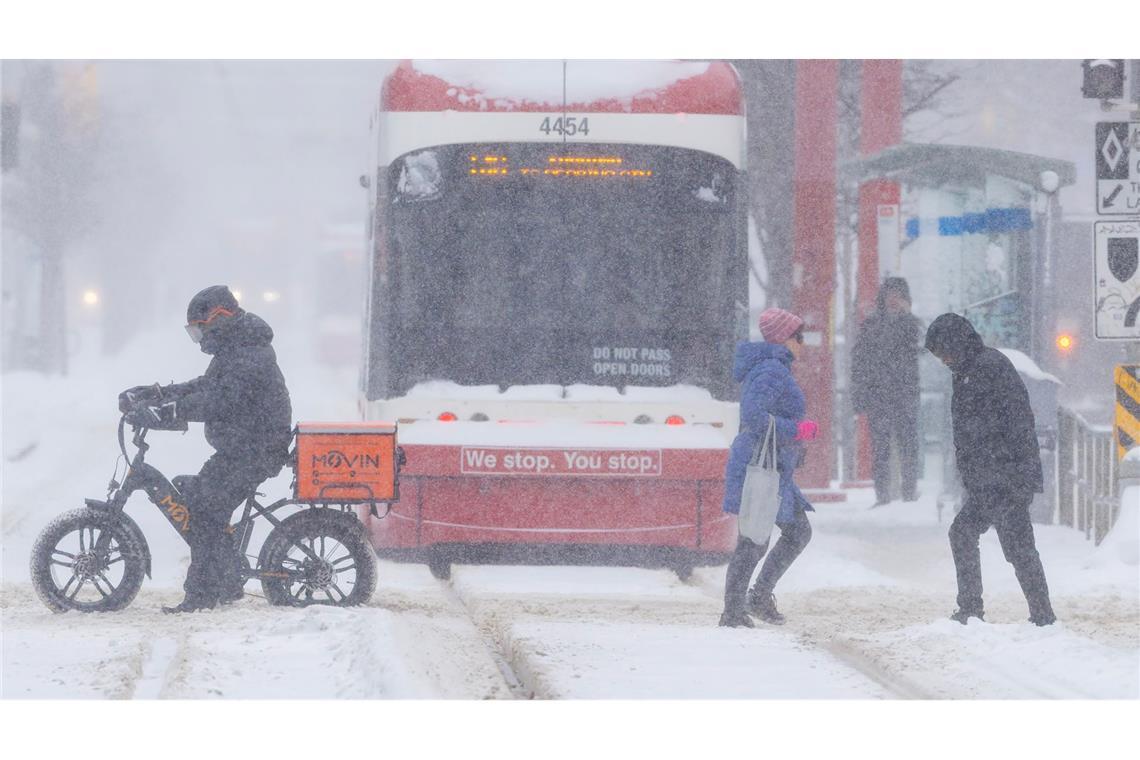 Menschen überqueren eine Straße an einem verschneiten Tag in Toronto, Kanada.
