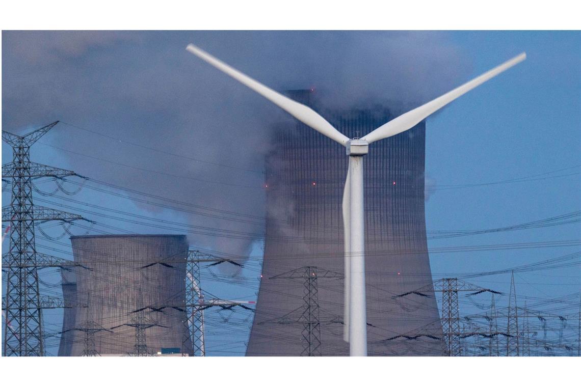 Welche Rolle spielt Deutschland in der globalen Klimakrise? Mit Fossilen in den Klim-Abgrund: Dampf steigt aus dem RWE Braunkohlekraftwerk Neurath bei Grevenbroich in Nordrhein-Westfalen. Im Vordergrund steht eine Windkraftanlage.