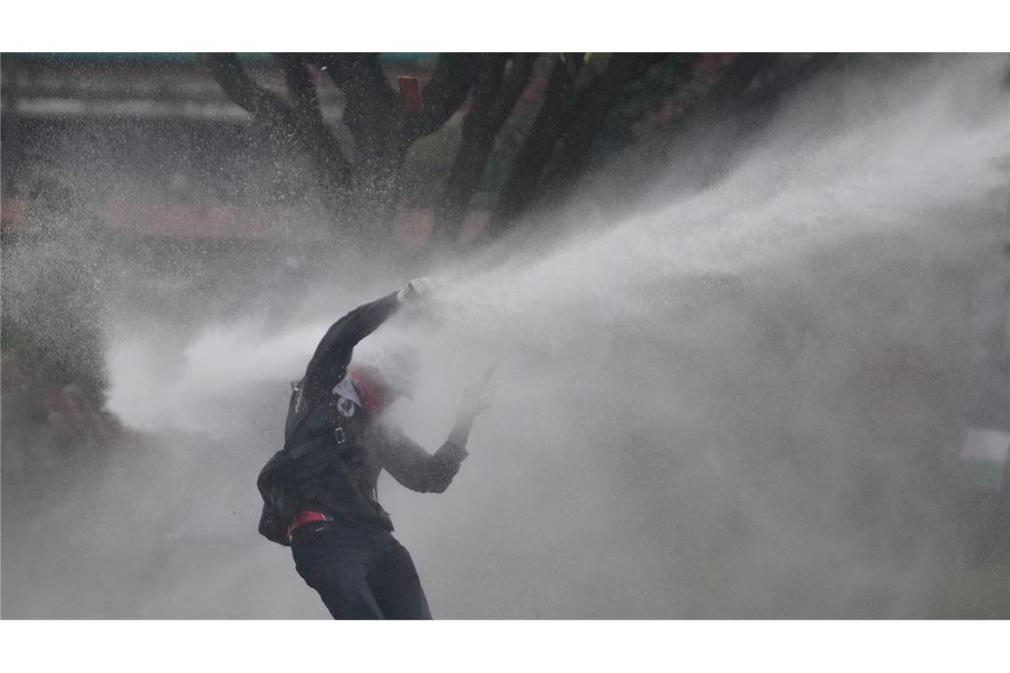 Mit voller Wucht: Ein Demonstrant wird bei Protesten gegen die Politik von Präsident Petro von einem Wasserwerfer getroffen.