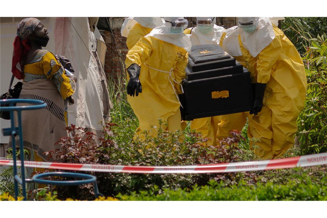 Mitarbeiter des Roten Kreuzes tragen in Schutzanzügen den Sarg einer an Ebola verstorbenen Person aus einem Gesundheitszentrum in Rwampara.