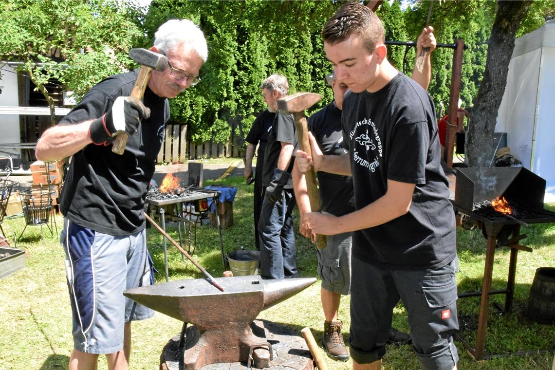 Mitglieder der Schmiedegruppe „Eisen und Feuer“ bearbeiten Eisen auf dem Amboss.