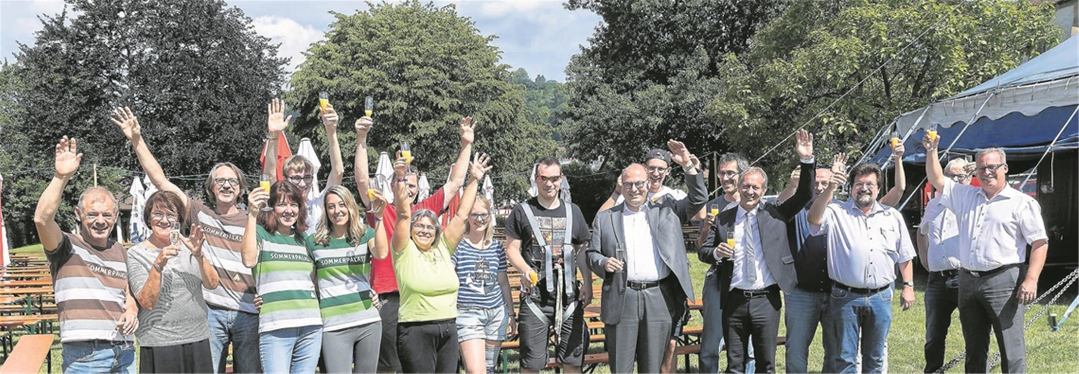 MURRHARDT (cs). Zwei Helfer des ehrenamtlichen Teams hatten sich auf die Höhen der vorderen Zeltmasten geschwungen, zwischen denen später das große Sommerpalastbanner angebracht werden sollte, viele weitere tummelten sich in der Murrhardter Festhalle am Rande des Stadtgartens, um alles für die festliche Sommerpalastküche vorzubereiten, während der harte Kern mit Vertretern der Stadtverwaltung und Unterstützern des Sommerpalasts am Mittwochvormittag zur Zelttaufe schritt. Bürgermeister Armin Mößner (vorne, Vierter von rechts) dankte den Sponsoren und stellte fest, dass der 24. Sommerpalast kulturell eine Menge zu bieten hat: Konzerte, Varieté und Kleinkunst, eine Auswahl, bei der sicher für jeden Geschmack etwas dabei sei. Ebenso bezog er die Sommerpalastpapas Hardy Wieland (links) und Kulturamtsleiter Uwe Matti (vorne, Zweiter von rechts), die das Festival einst aus der Taufe gehoben haben, sowie die rund 300 ehrenamtlichen Helfer in seinen Dank mit ein, deren Einsatz aller Ehren wert sei. „Jetzt wünsche ich uns fünf großartige Sommerpalasttage“, sagte Mößner. Mit dem gebührenden Schwung hat am Abend die „Amsterdam Klezmer Band“ das Murrhardter Kulturfestival eröffnet. Infos zum kompletten Programm mit den weiteren Vorstellungen finden sich im Netz unter www.sommerpalast.de. Foto: J. Fiedler