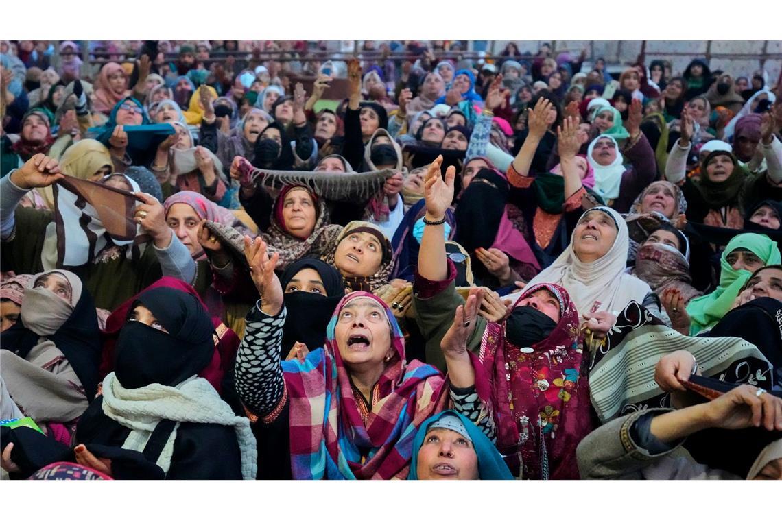 Muslimische Gläubige aus Kaschmir beten, während ein Oberpriester eine Reliquie zeigt.