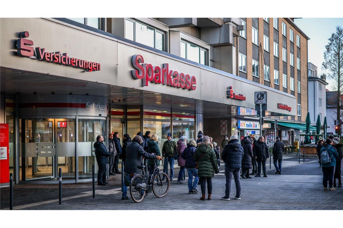 Nach einem Einbruch in den Tresorraum einer Bankfiliale in Gelsenkirchen warten Menschen vor dem Eingang auf Informationen.
