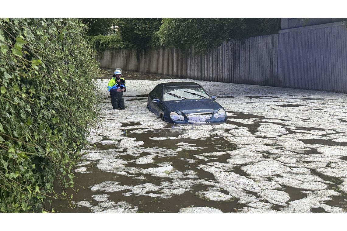 Autos im Südwesten stärker von Unwetterschäden betroffen Nach schweren Unwettern steht ein Auto auf einer überfluteten Straße in Immenstadt. (Archivbild)