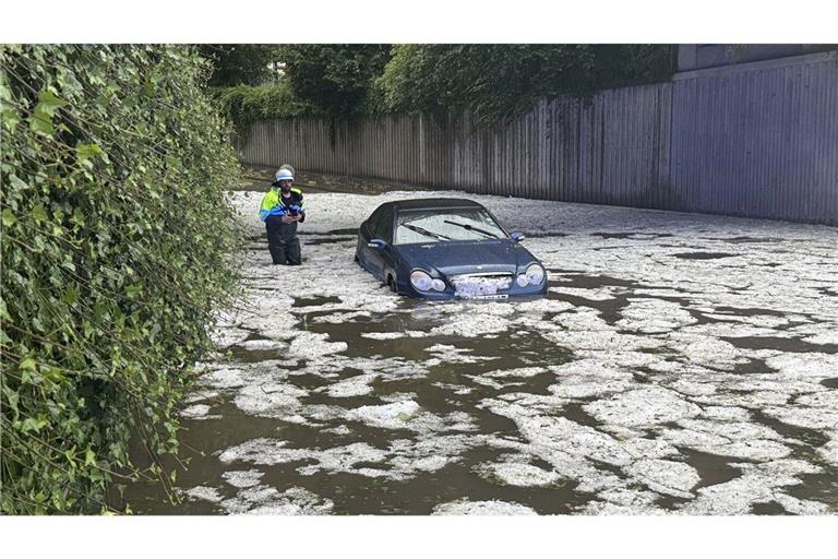 Nach schweren Unwettern steht ein Auto auf einer überfluteten Straße in Immenstadt. (Archivbild)