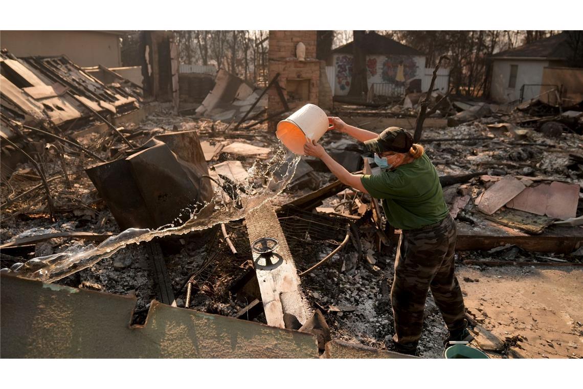 Brände in den USA: Kurze Entspannung, weiterhin große Gefahr Nancy Belanger gießt Wasser auf das vom Feuer verwüstete Grundstück eines Nachbarn im Stadtteil Pacific Palisades von Los Angeles.