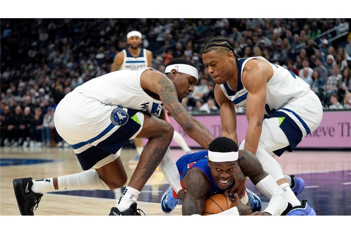 Bilder des Tages NBA Basketball: Detroit Pistons-Guard Dennis Schröder (M), fällt, während Minnesota Timberwolves-Forward Jaden McDaniels (l) und Guard Jaylen Clark (r) um den Ballbesitz kämpfen.