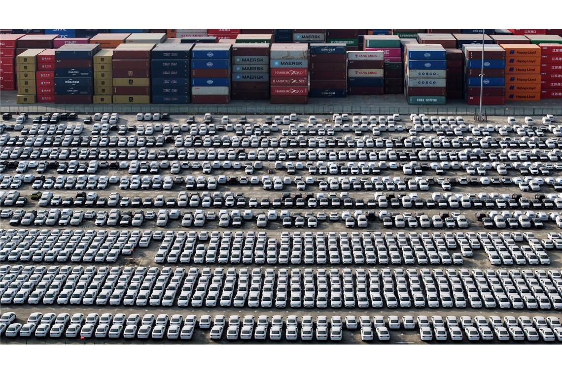 Neue Volvo-Fahrzeuge stehen neben Containern und warten auf ihre Verschiffung im Jangtse-Hafen in der Stadt Nanjing in der ostchinesischen Provinz Jiangsu.