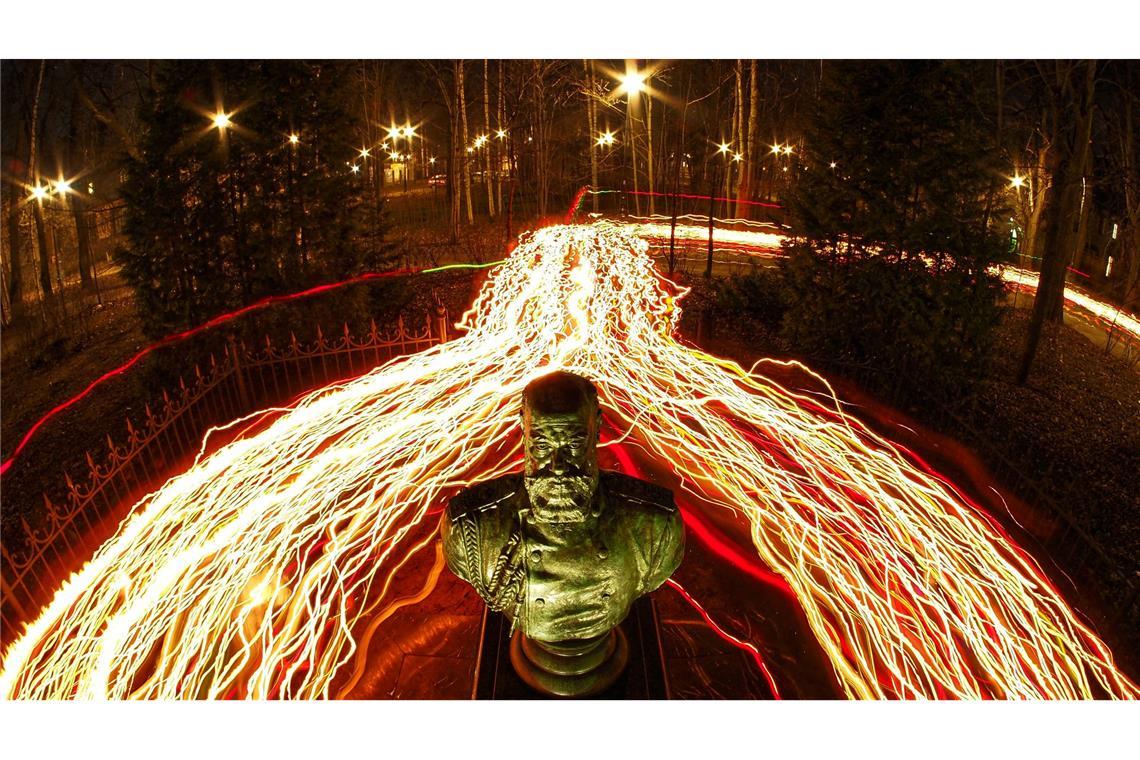 Orthodoxe Gläubige gehen während des orthodoxen Mitternachtsgottesdienstes zu Ostern mit Kerzen an einer Büste des russischen Zaren Alexander III. in St. Petersburg vorbei.  (Foto mit Langzeitbelichtung)