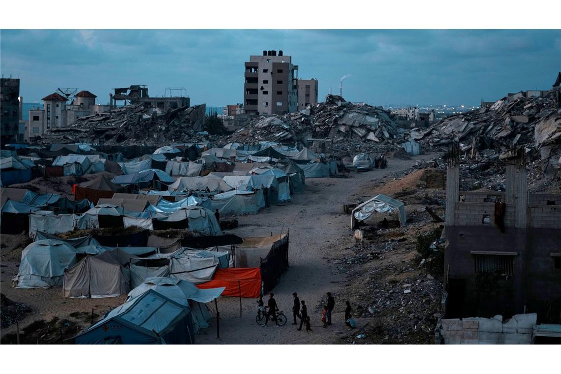 Bilder des Tages Palästinenser, die durch die israelische Luft- und Bodenoffensive auf den Gazastreifen vertrieben wurden, gehen in der Abenddämmerung über einen Platz in einem behelfsmäßigen Zeltlager.