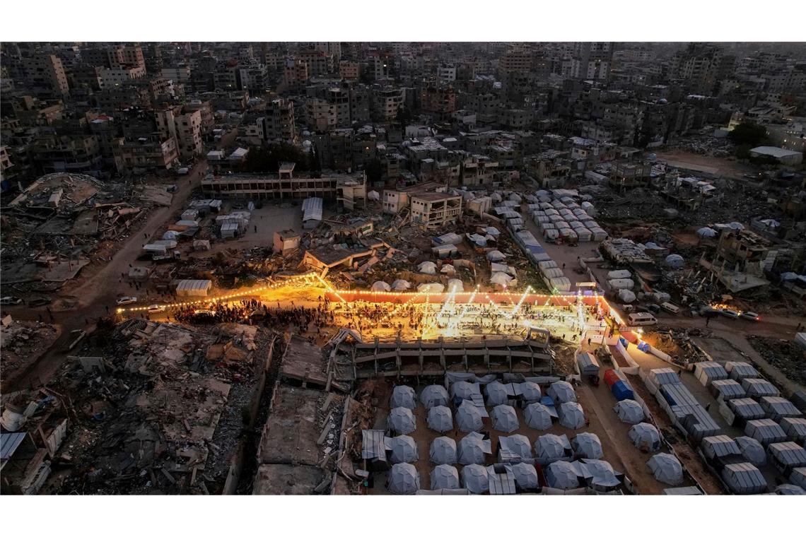 Bilder des Tages Palästinenser sitzen an einem großen Tisch, umgeben von Zelten und den Trümmern zerstörter Häuser und Gebäude, während sie sich zum Iftar, dem Fastenbrechen, während des Ramadan versammeln.