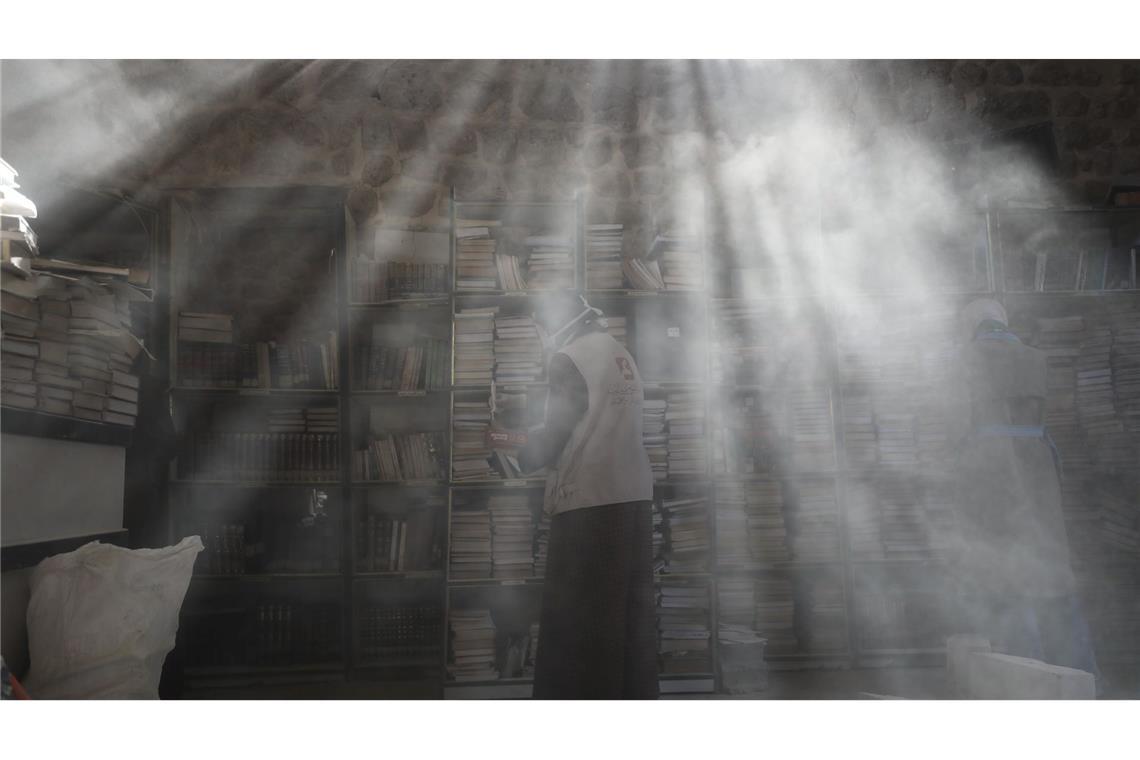 Palästinensische Freiwillige entstauben in der Bibliothek der Großen Omari-Moschee in der Altstadt von Gaza-Stadt Bücher, um beschädigte Bestände nach der zweijährigen Bombardierung des Gazastreifens zu retten und zu restaurieren.