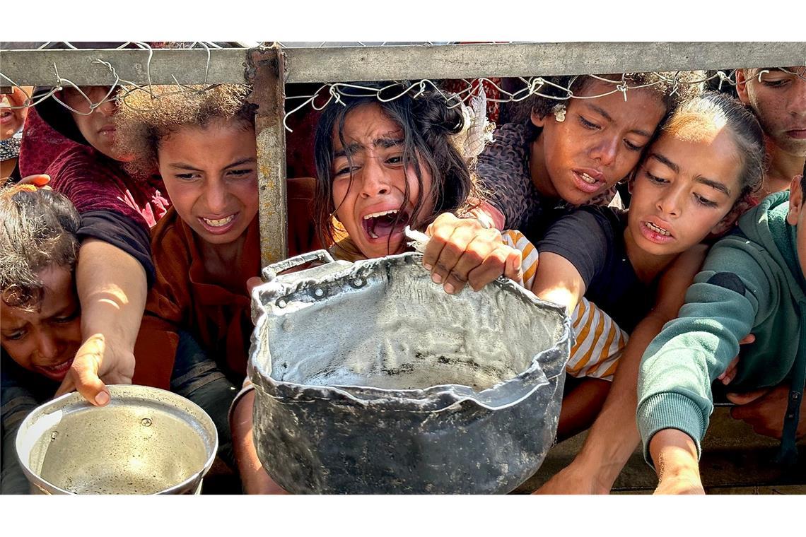 Bilder des Tages Palästinensische Kinder versuchen im Gebiet Al-Mawasi im Gazastreifen, mit ihren Töpfen Nahrungsmittel zu bekommen, die von einer Wohltätigkeitsorganisation verteilt werden.