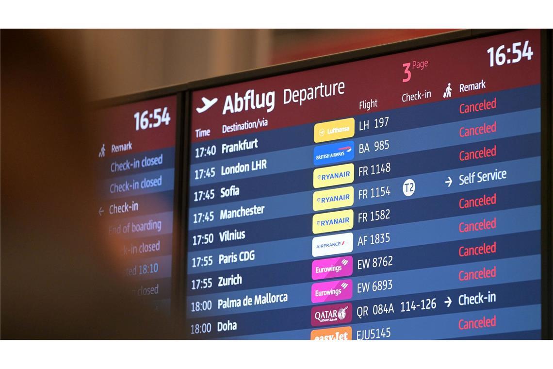 Passagiere blicken auf eine Anzeigetafel am Hauptstadtflughafen BER.