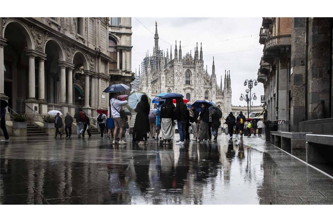 Heftiger Regen im Norden Italiens – auch Urlaubsregionen betroffen Passanten gehen im Zentrum von Mailand mit Regenschirmen. (Archivbild)